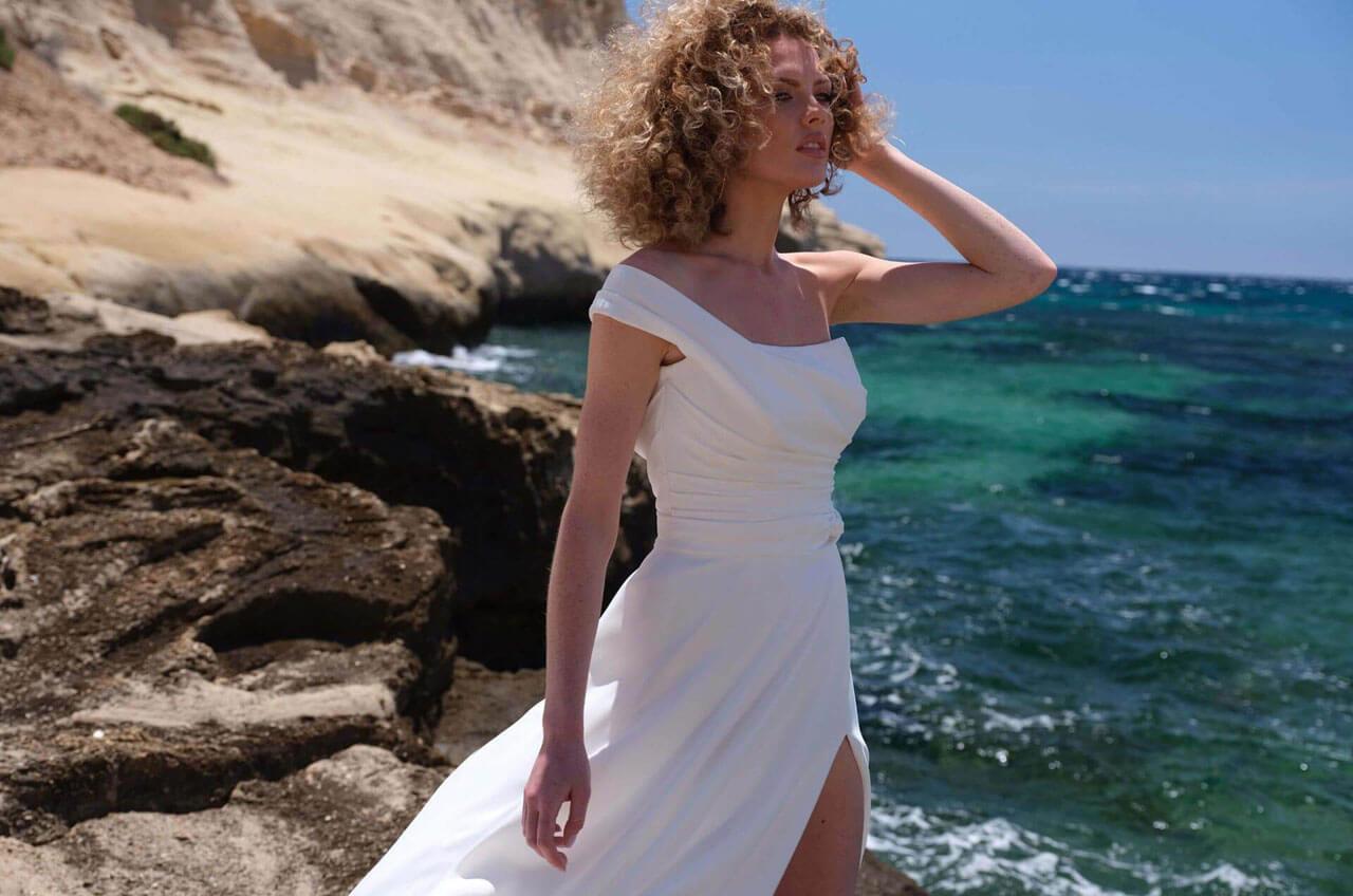 Lilurose Brautkleider aus der Andalusia Kollektion Frau im weißen Brautkleid am Meeresufer.
